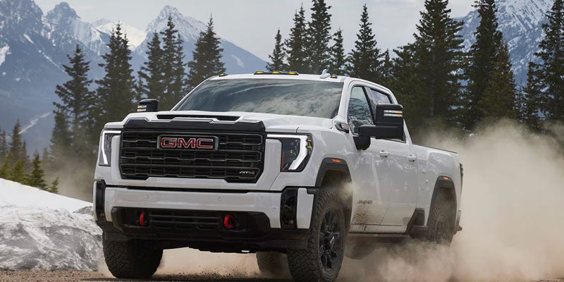 Heavy-duty 2026 GMC Sierra HD driving through challenging off-road conditions, illustrating traction and control.